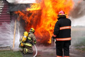 Abandoned house in flame with firefighters in action