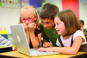 Two young girls and a boy use a laptop computer