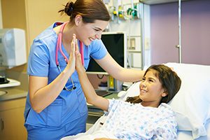 Happy Young Girl Talking To Smiling Female Nurse In Hospital Room