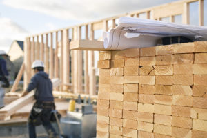 Photo of construction site, worker, stacks of lumber