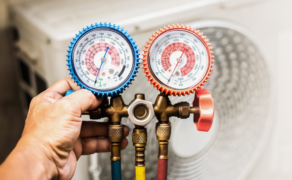 Photo of man's hand holding measuring equipment for filling air conditioners