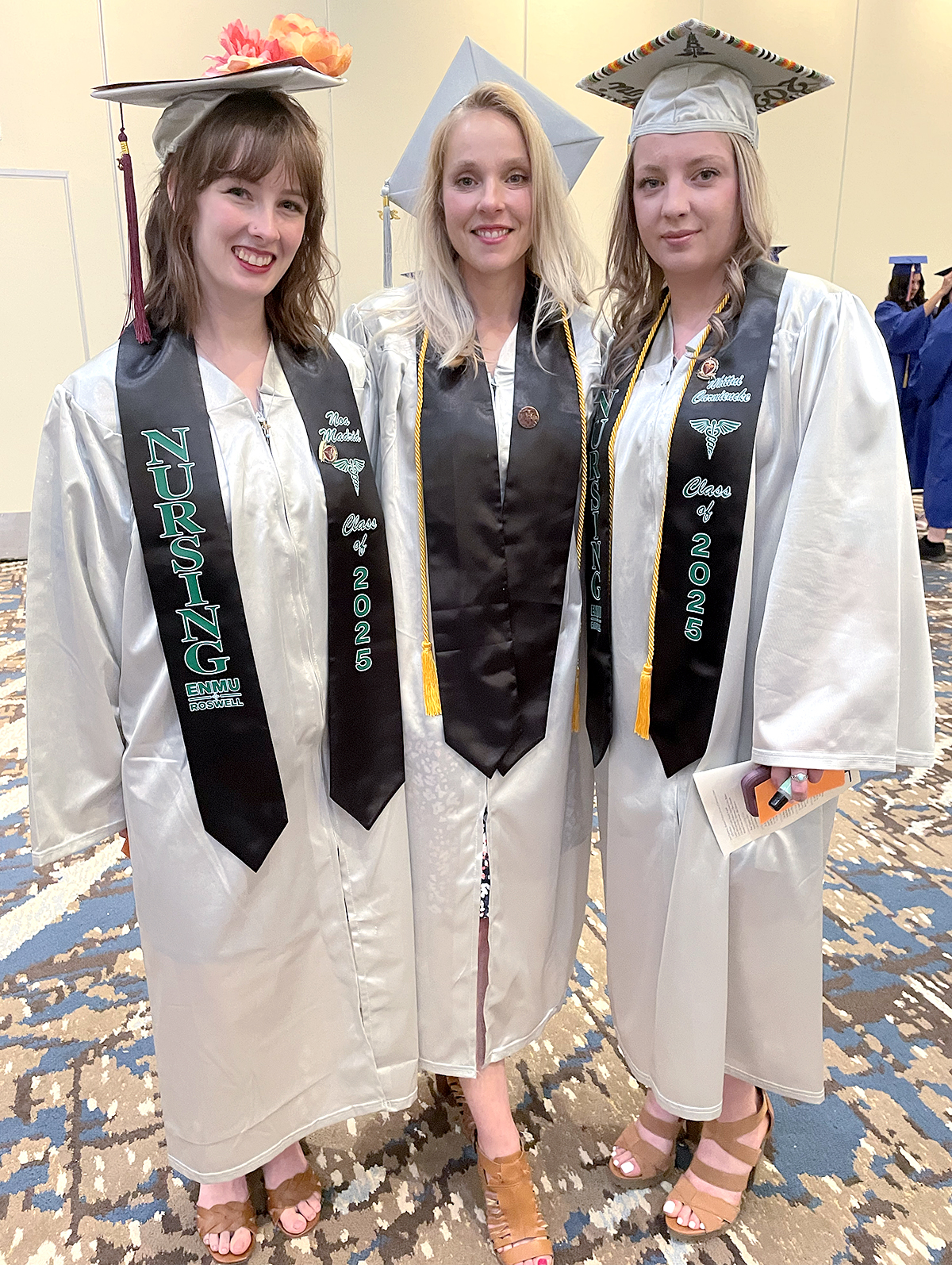 Photo of Noa Madrid, Rebecca Canavan and Whittni Carmiencke in their caps & gowns at the 2025 graduation ceremony